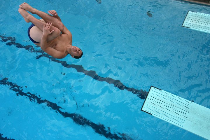 A male diver performs a reverse tuck from 3-meter springboard